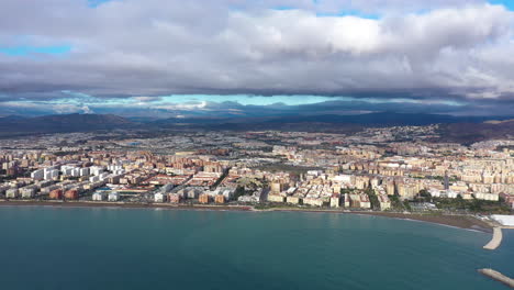 Luftaufnahme-Von-Malaga,-Strand-Der-Barmherzigkeit,-Dunkler-Sand,-Stadt-Im-Hintergrund,-Küstenstadt